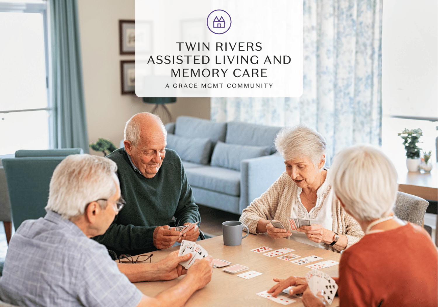 Four seniors playing cards around a table in a bright living room; Twin Rivers Assisted Living and Memory Care logo overlaid at the top center.